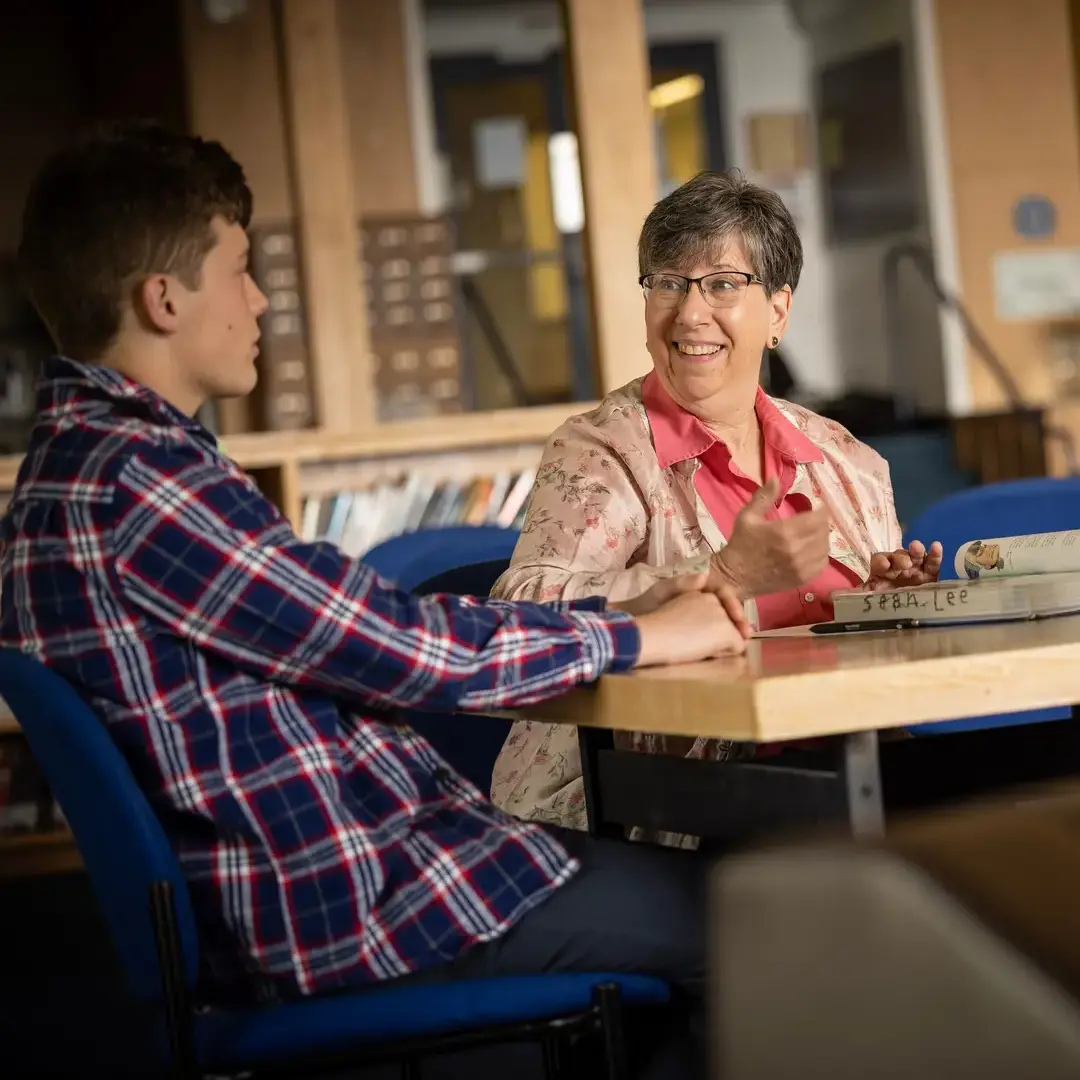 Student talking with teacher in library