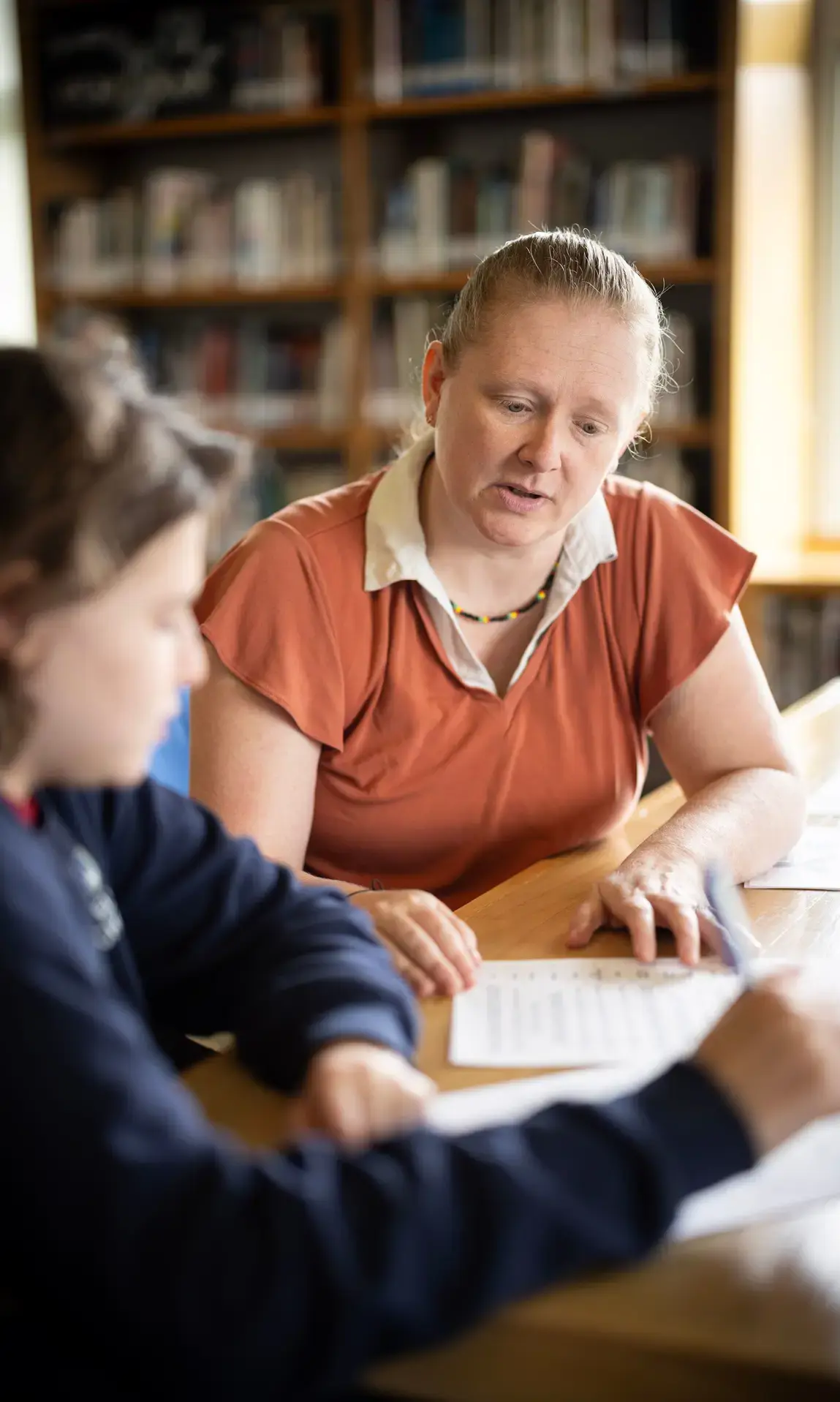 Teacher assisting student in library