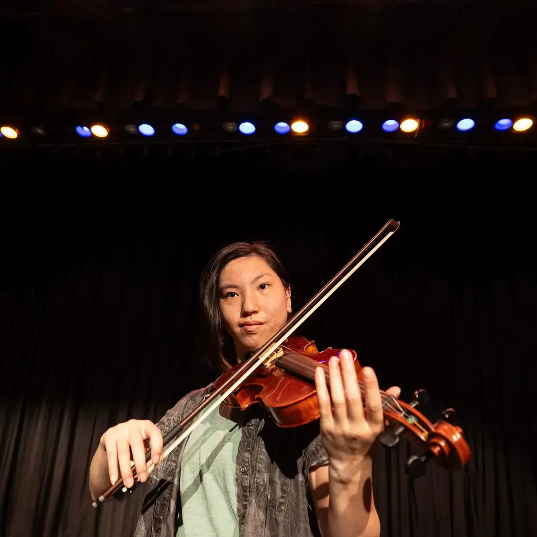 Student playing violin on stage