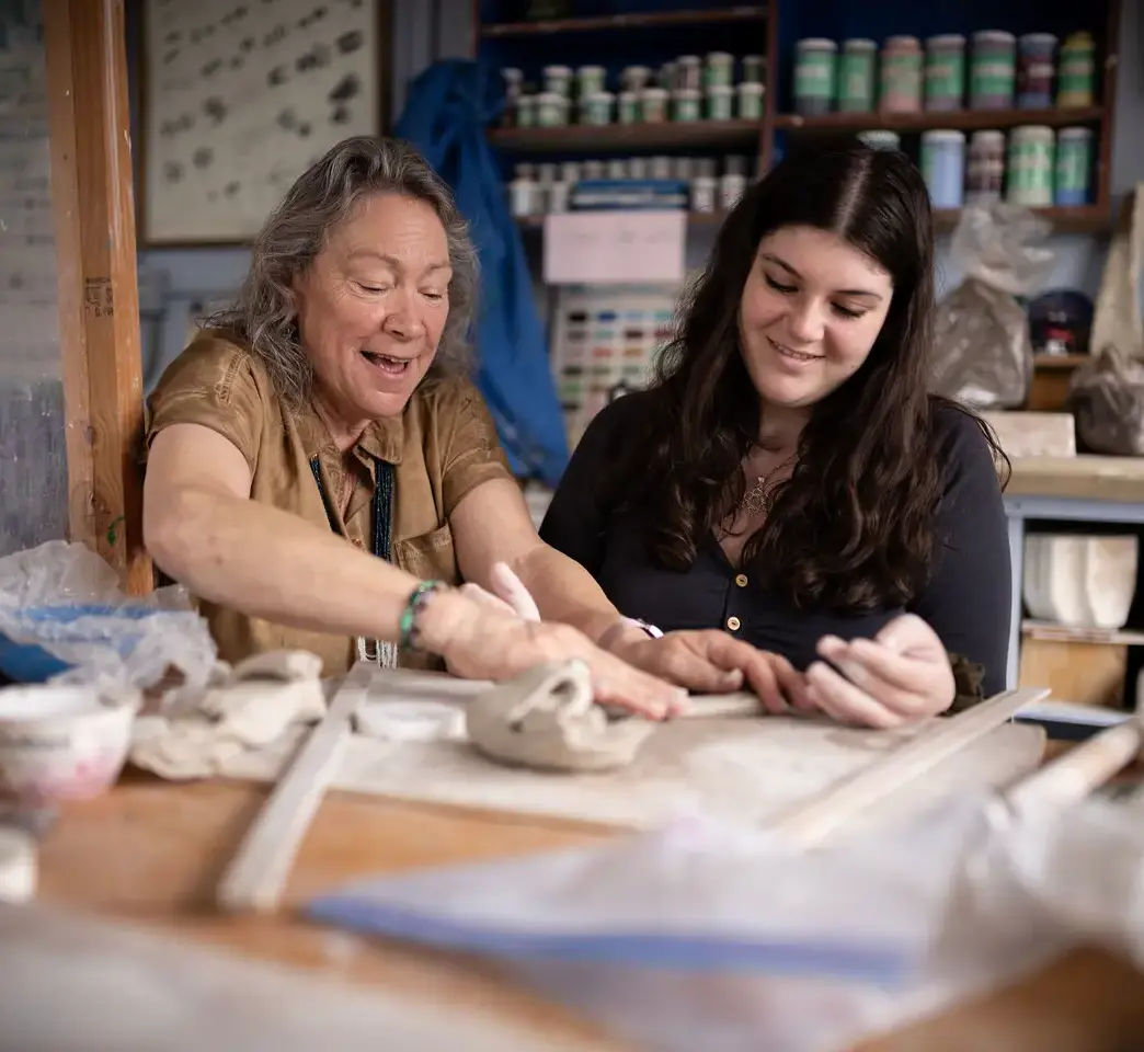 Teacher and student working on pottery together