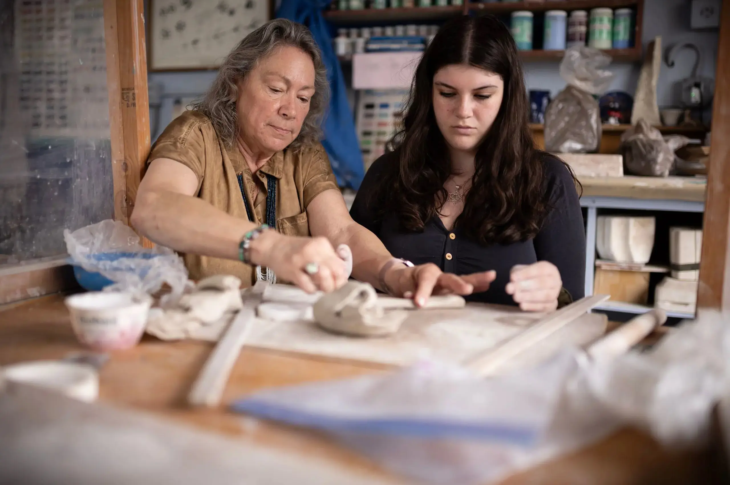 Student working on ceramics with teacher