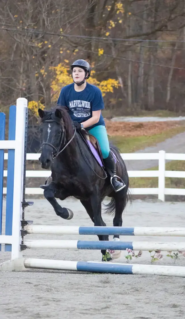 Student doing show jump on horse