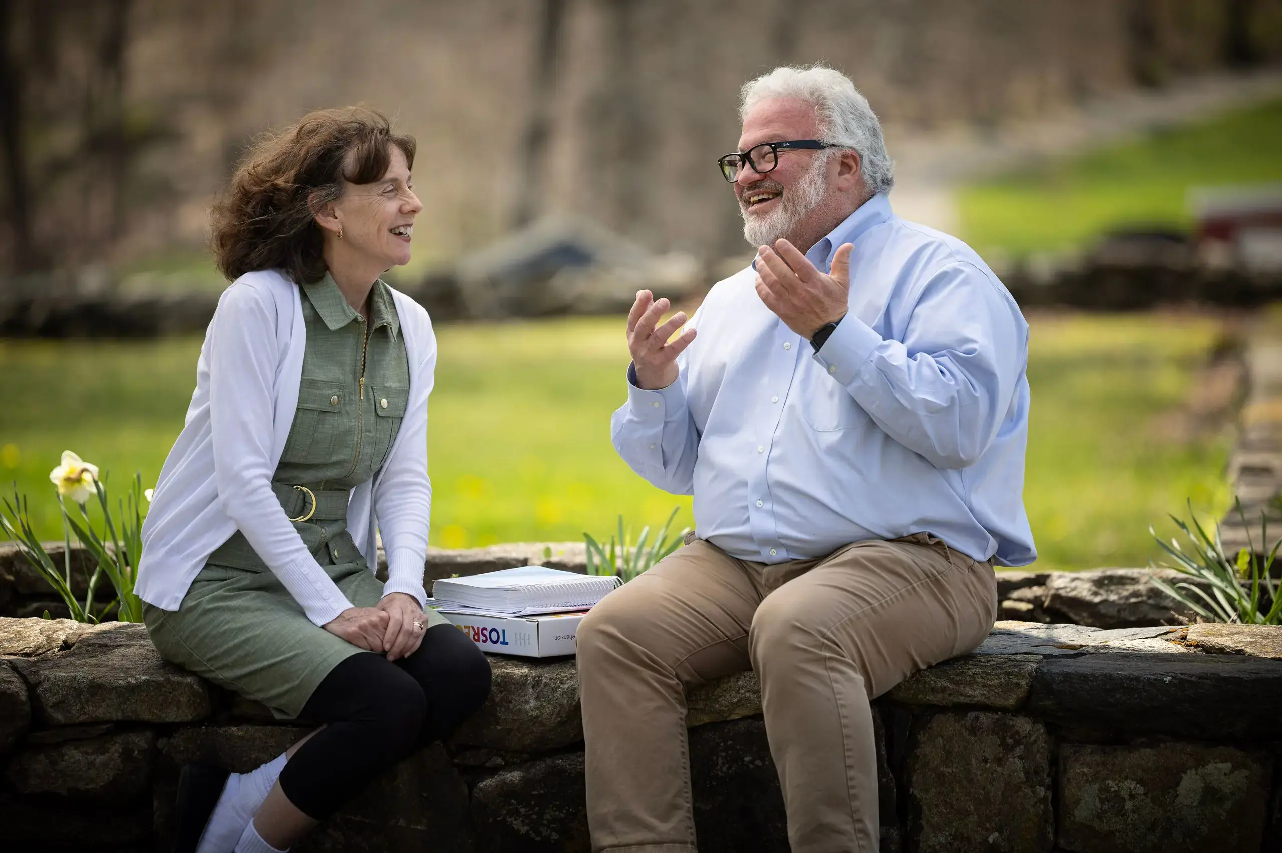 Faculty discussing on bench by lake