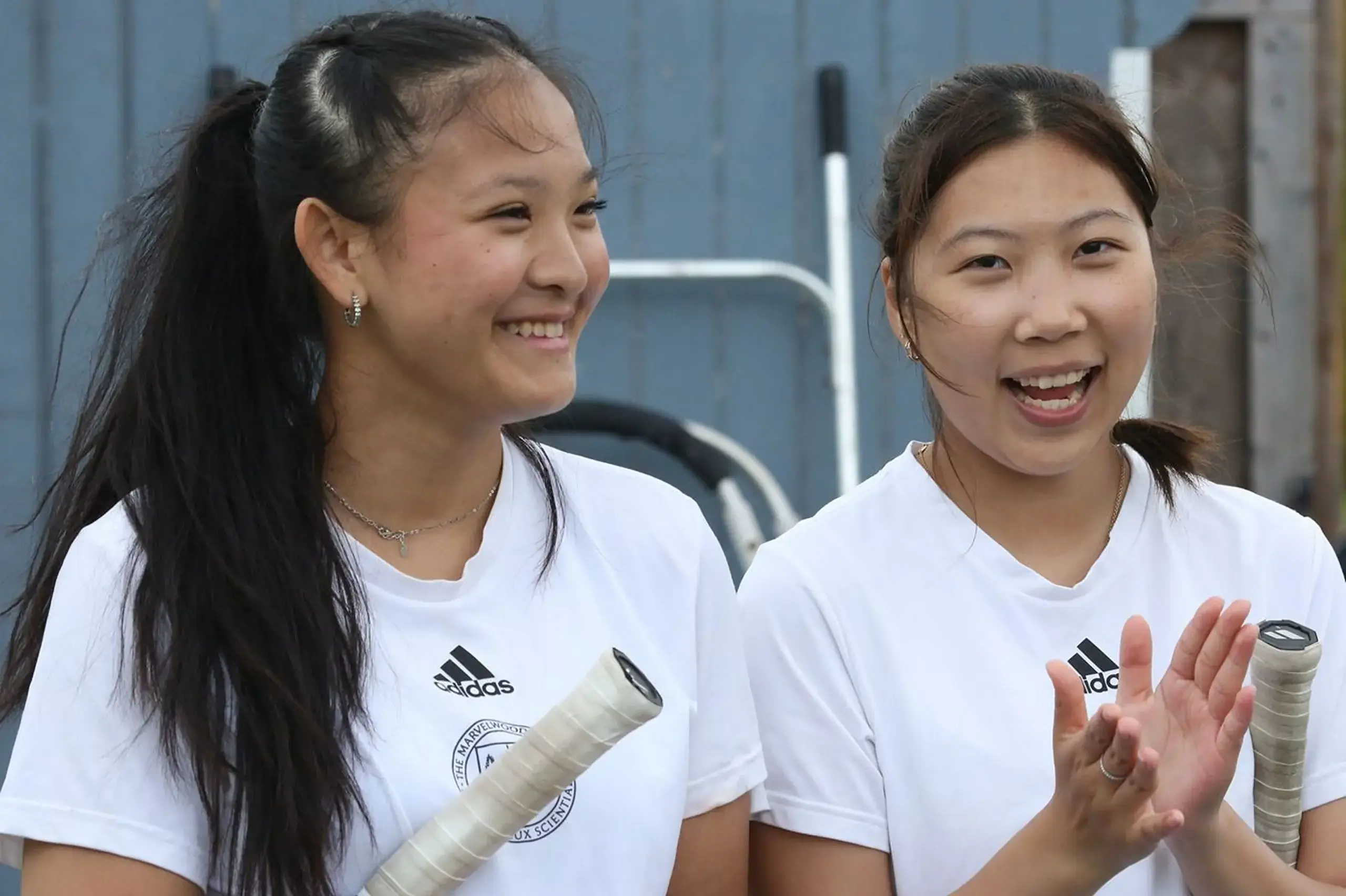 Girls smiling together with tennis rackets