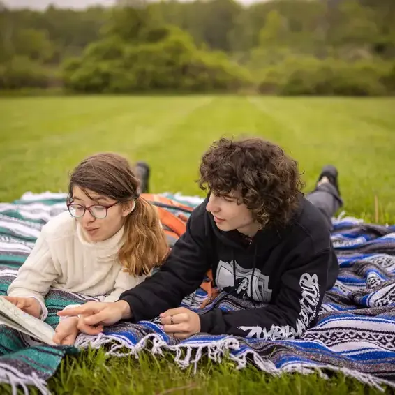 Students reading book in field