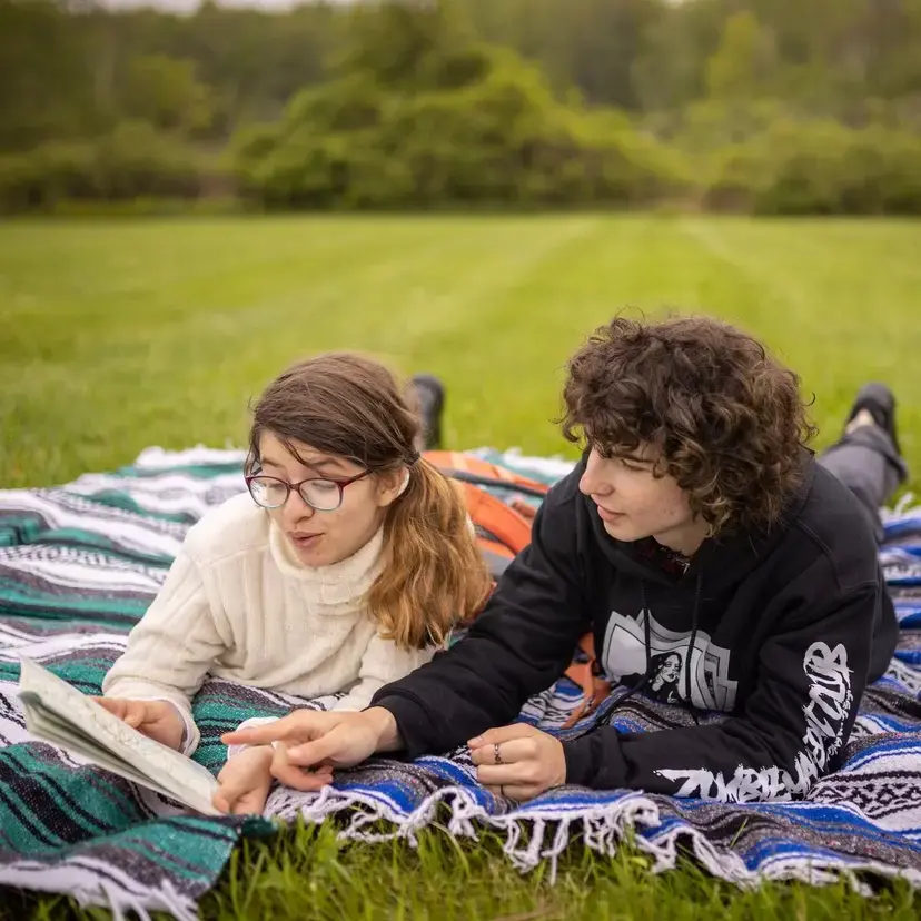 Students reading book together on lawn