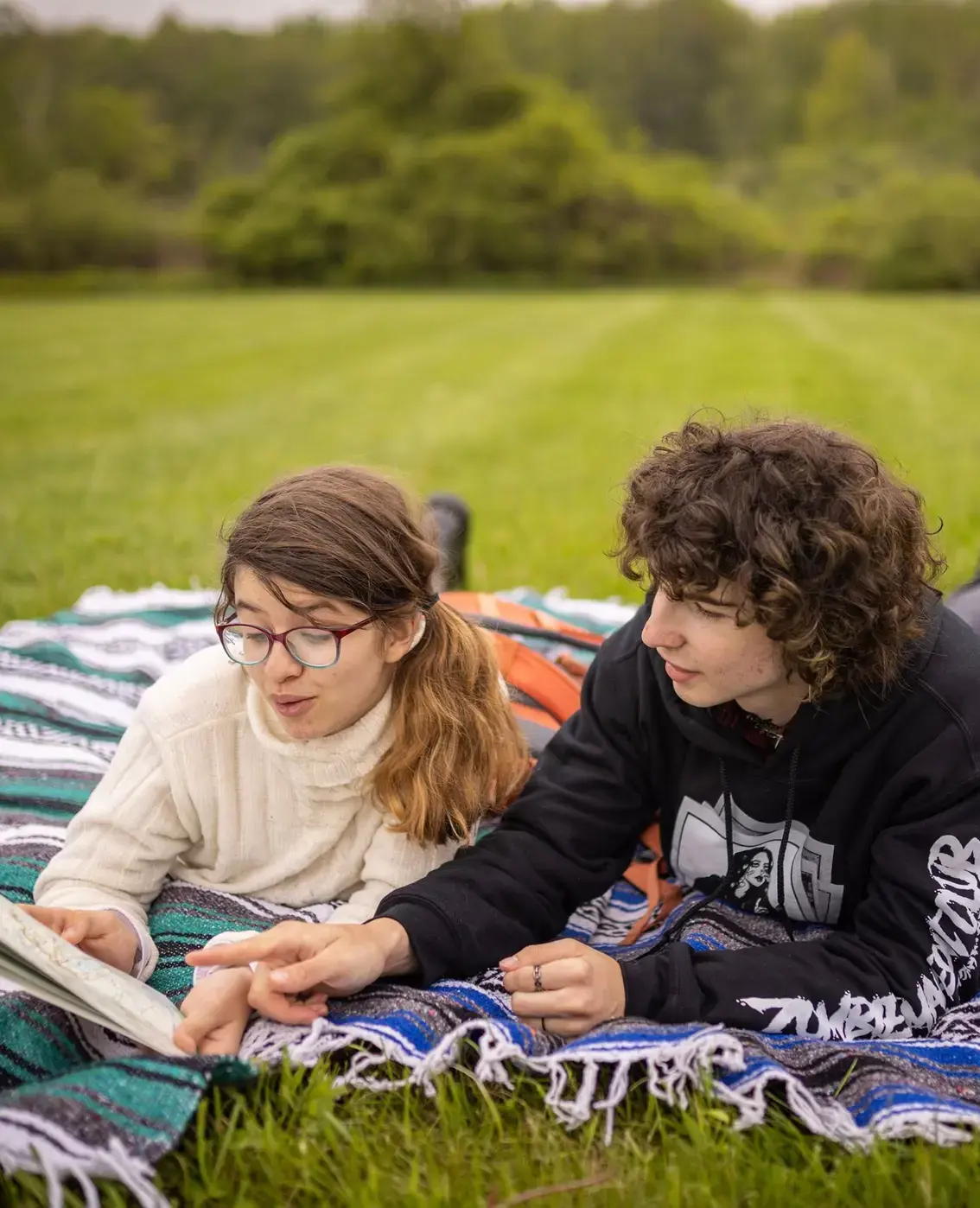 Students reading book together in field