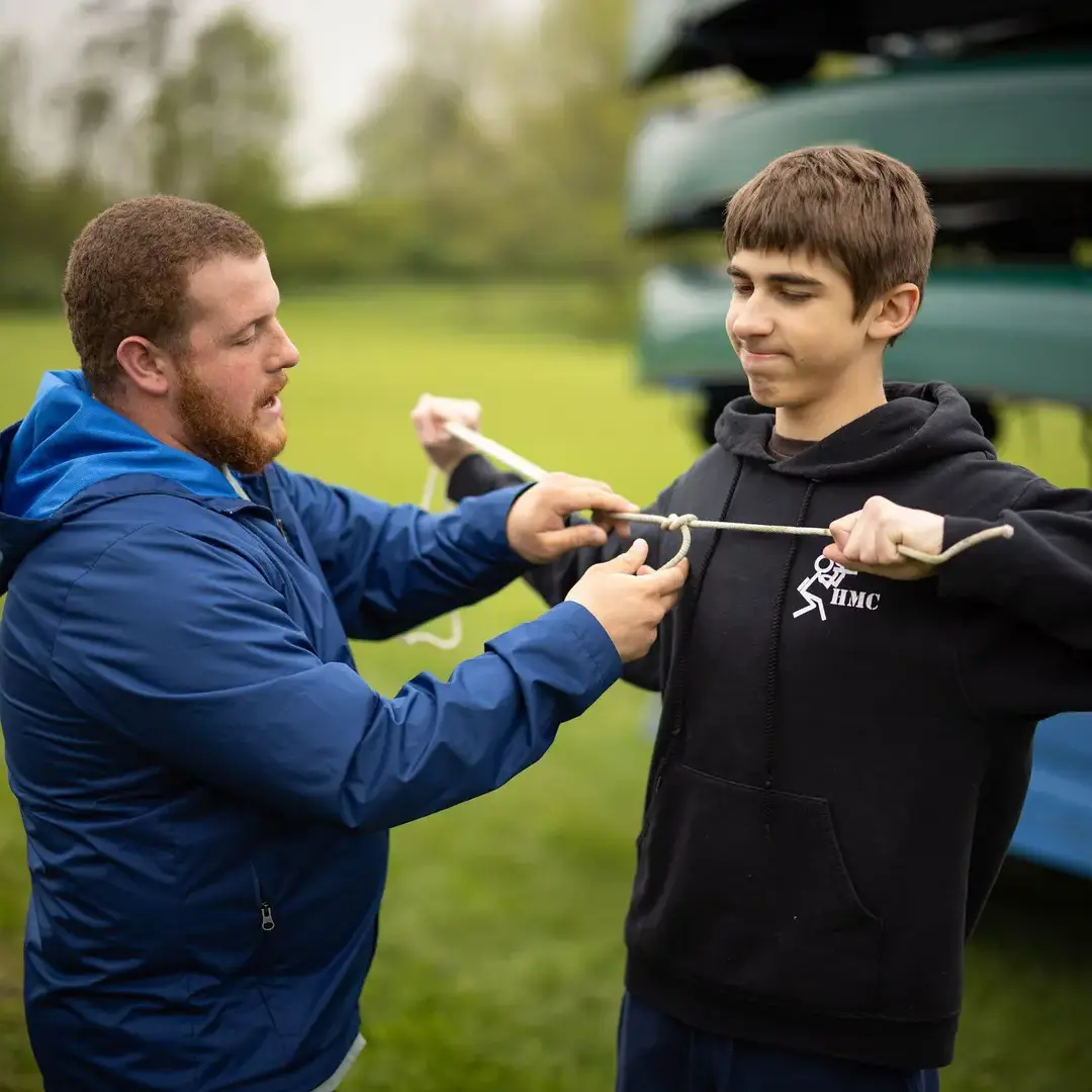 Teacher helping student tie nautical knots